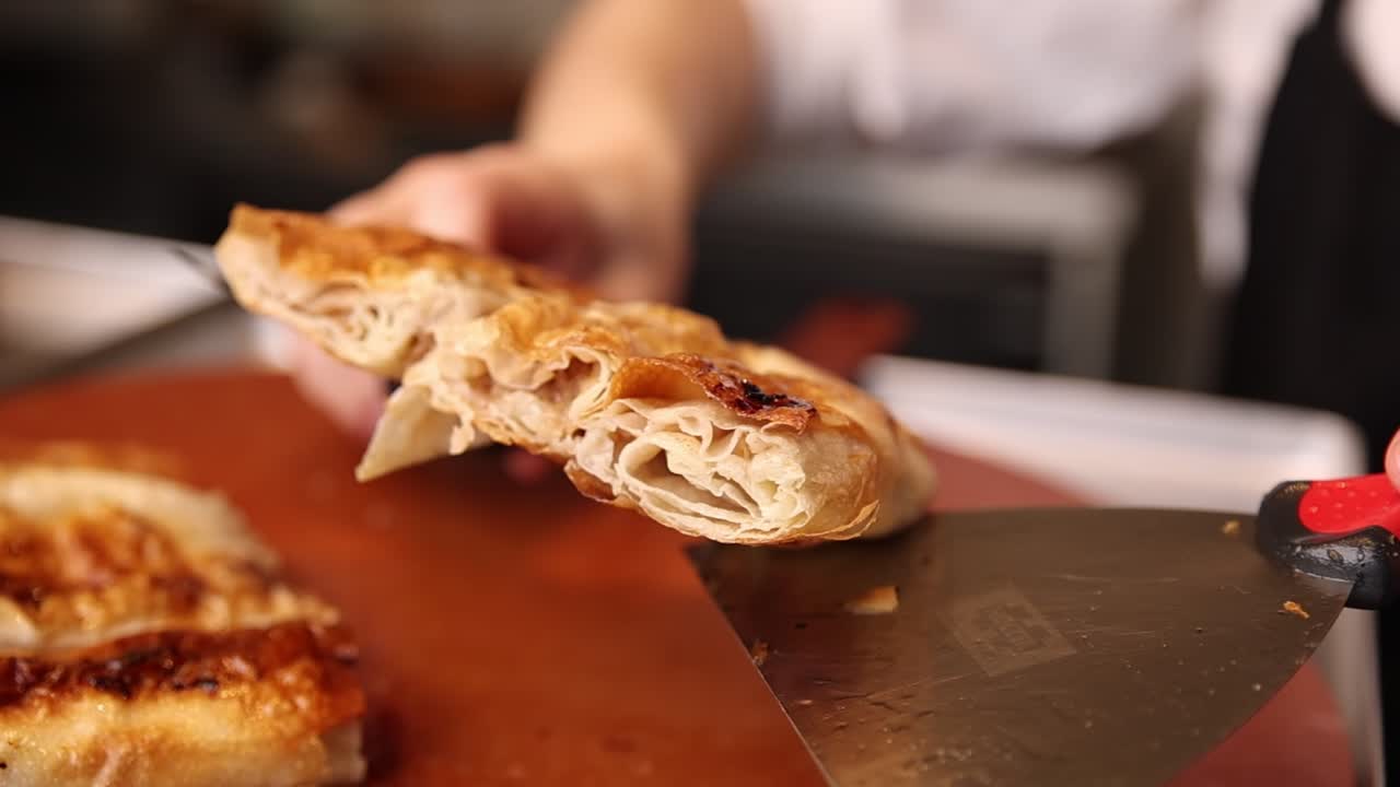 Primo piano di una mano che taglia un dolce dorato appena sfornato.