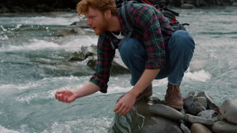 escursionista maschio che si riposa al fiume in montagna