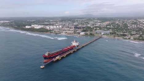 oil tanker docked at port of haina with industrial infrastructure and urban landscape, energy distribution, maritime transport, and trade, dominican republic. aerial orbiting