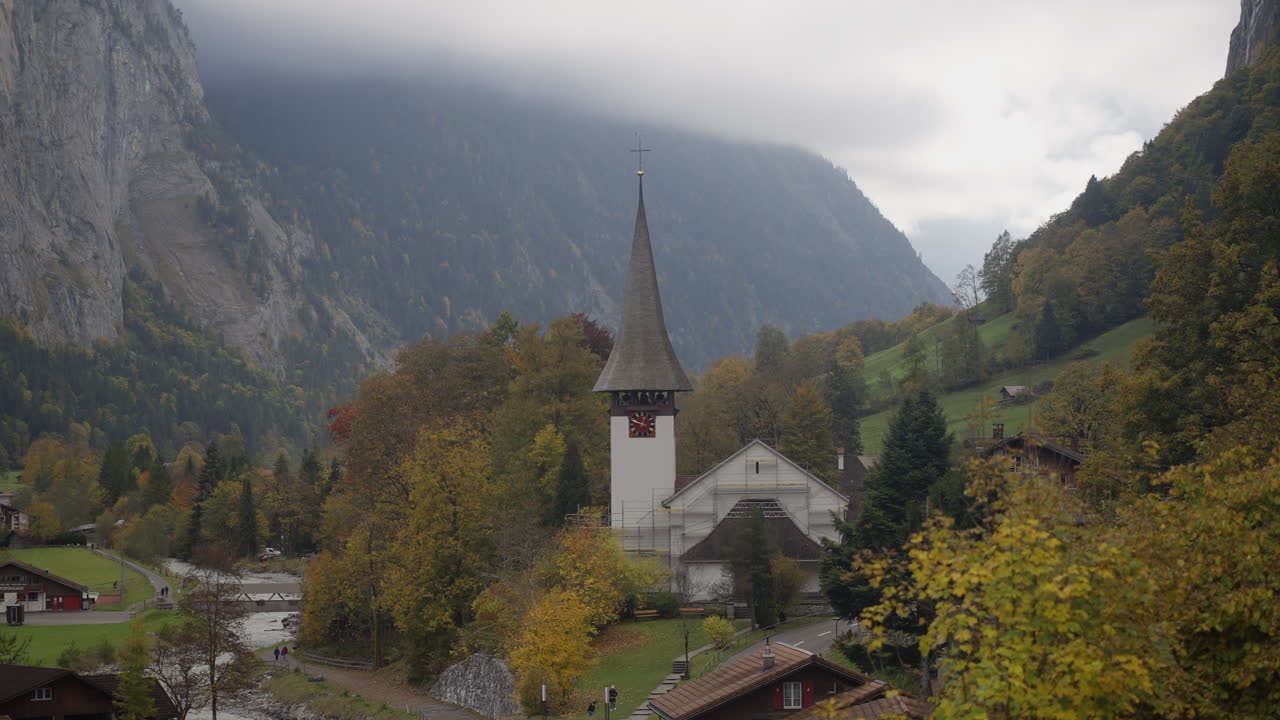 Famous valley view of Lauterbrunnen with iconic church, alpine homes, cliffs, and river during an autumn day