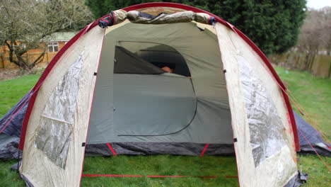 A-mature-bald-man-zipping-up-closing-a-tent-door-on-a-camping-trip-at-a-campsite-in-the-countryside