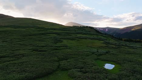 Aerial-panoramic-dolly-above-calm-alpine-pools,-ascend-to-beautiful-sun-flare-light-spreads-across-guanella-pass-colorado-mountains