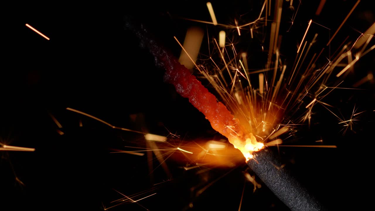 Scintille di fuoco bengala ardenti su sfondo nero, ripresa ravvicinata in 4K, slow motion