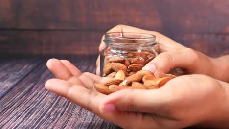 pouring almonds from a glass jar into hands