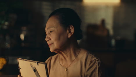 elderly woman reminiscing while looking at an old photo in a warm, nostalgic moment
