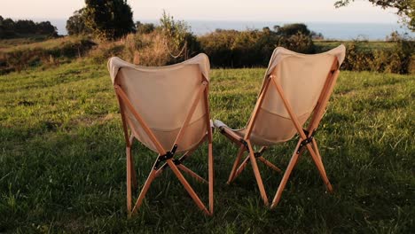 dos sillas vacías con vistas a un campo de hierba con vistas al océano