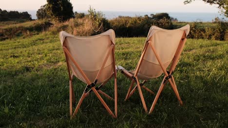 two empty chairs overlooking a grass field with ocean view