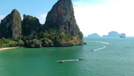 low aerial shot of long tail boat and large limestone karsts in railay beach, ao nang, krabi, thailand