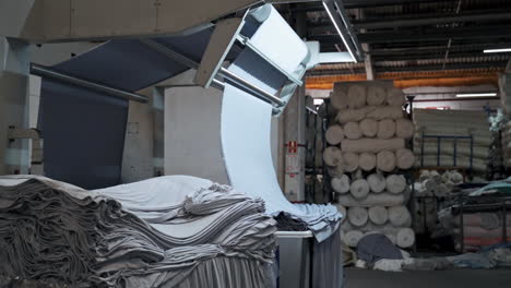 máquina industrial está colocando tela tejida azul, doblando ropa automáticamente en fábrica en cámara lenta