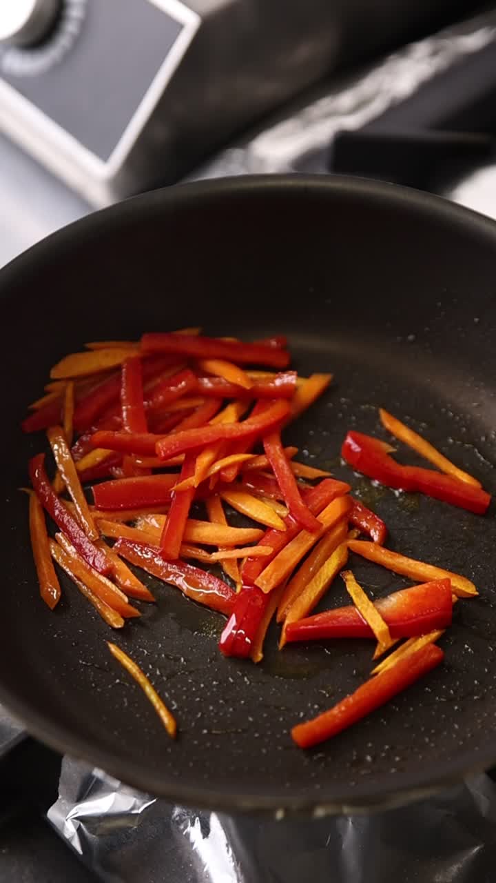 Geschnittene rote und orange Paprika braten in einer Pfanne