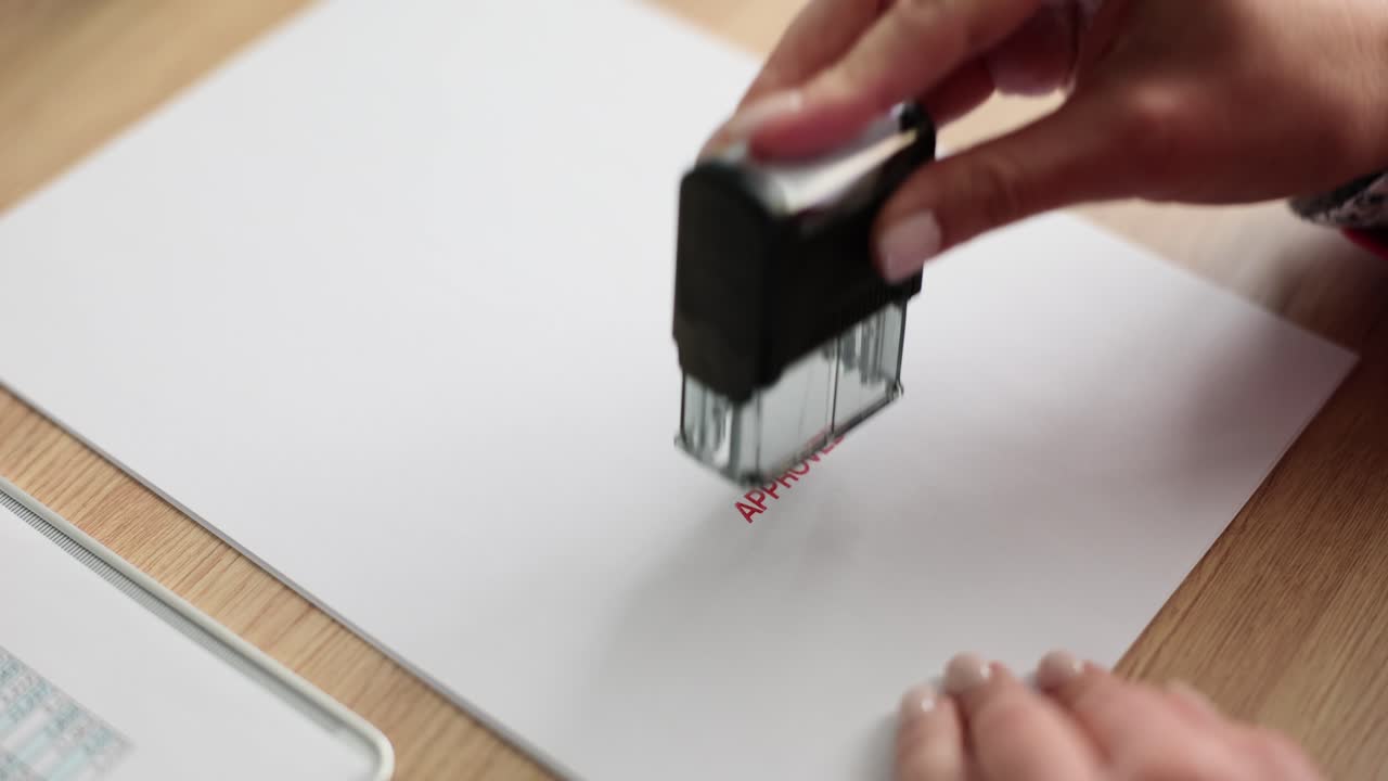 女性がオフィス内で書類に承認スタンプを押す。