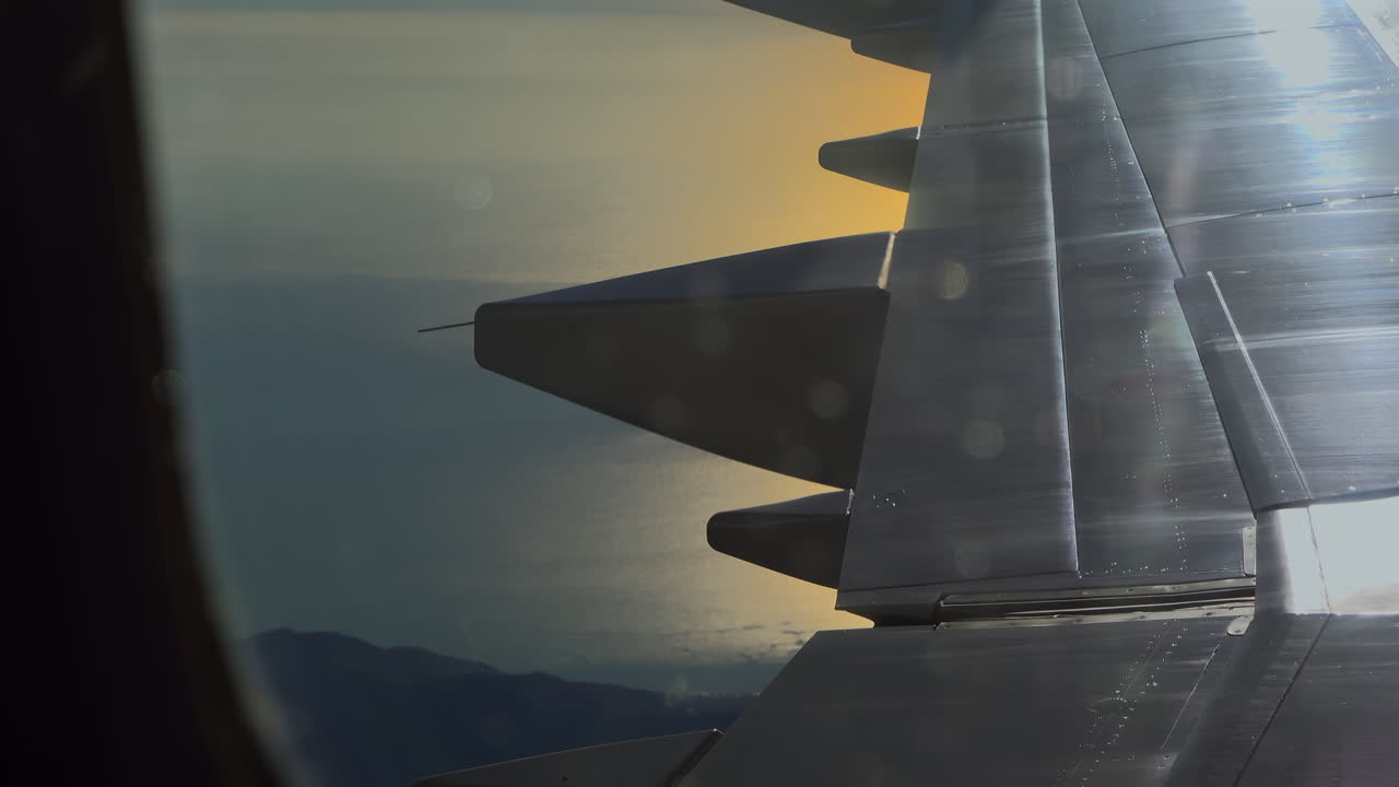 View from an airplane window of the sunset reflecting on the sea