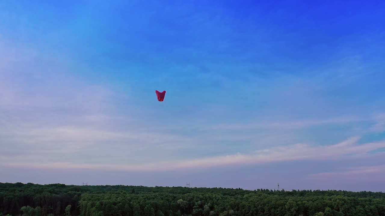 Paper lanterns floating in sky. Aerial view of single floating lantern against forest