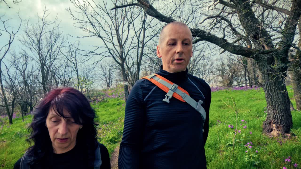 Middelbaar stel dat samen wandelt in een bloeiend lentebos. Concept van gezond ouder worden, actief blijven, fysieke fitheid en vitaliteit in de natuur.