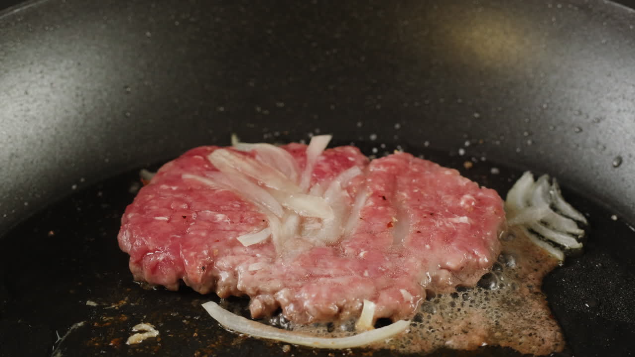 Cooking a Raw Hamburger Pattie with Onions in a Pan