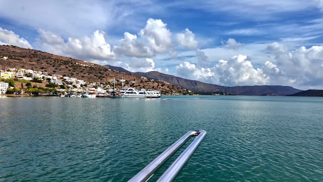 Panning view of Plaka village with hills, blue sky, sea, and charming buildings