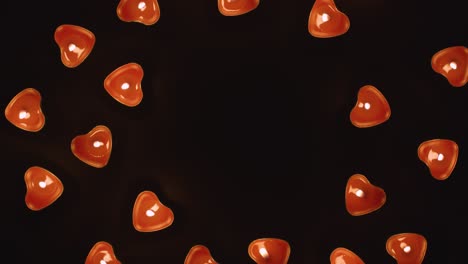 overhead shot of romantic lit heart shaped red candles revolving on black background with copy space