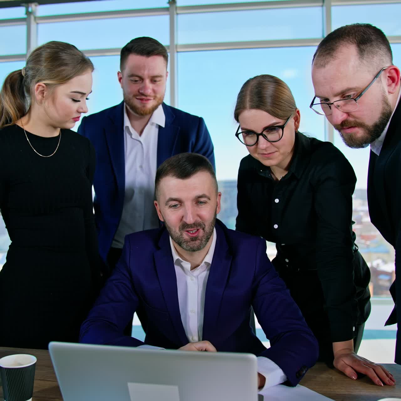 Positive entrepreneurs work together in office. Group of young business men and women look at a laptop and discuss new ideas. Business meeting