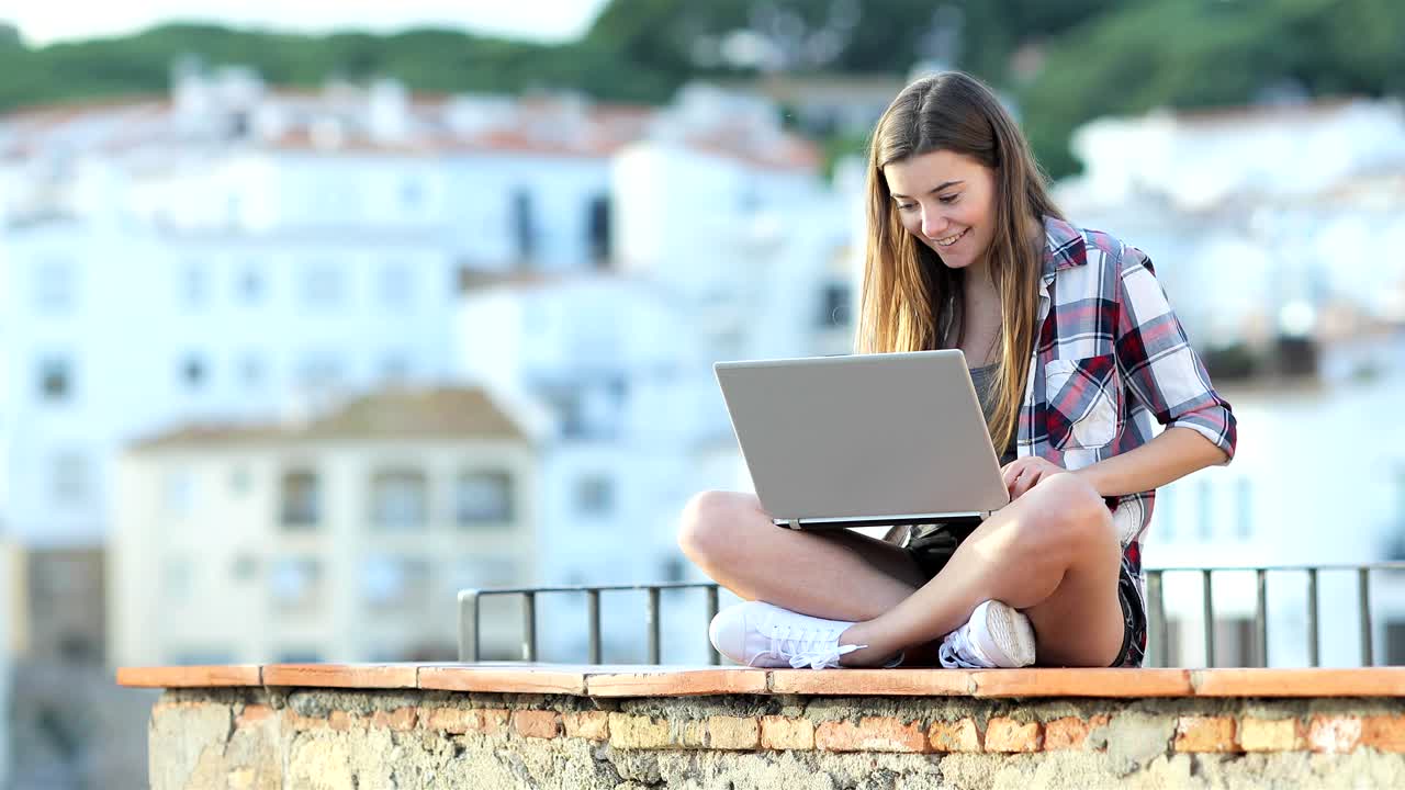 adolescente feliz escribiendo en una computadora portátil en vacaciones