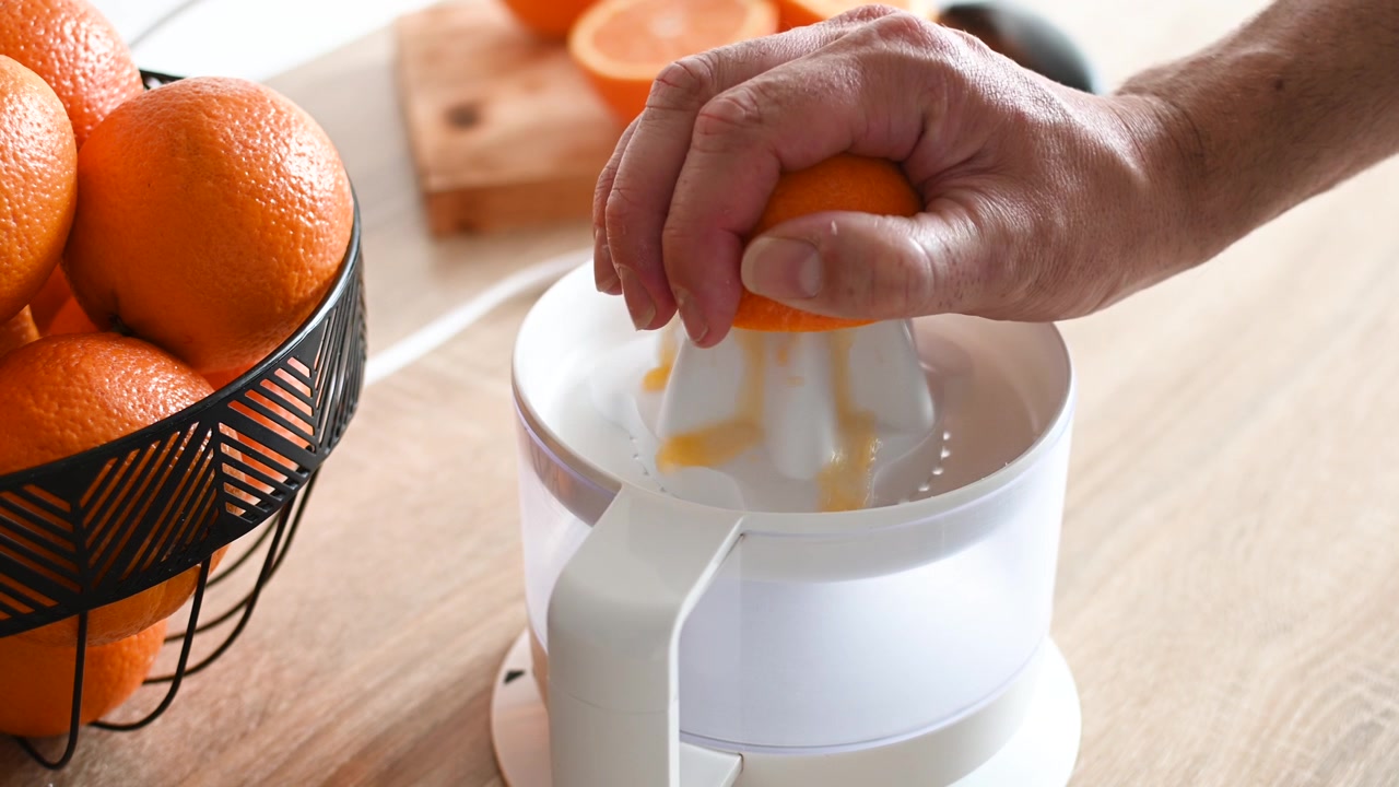 Hombre exprimiendo una naranja para el desayuno
