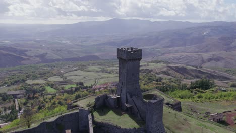 Flying-past-stone-medieval-fort-tower-in-beautiful-Italy-countryside,-Fortezza-di-Radicofani