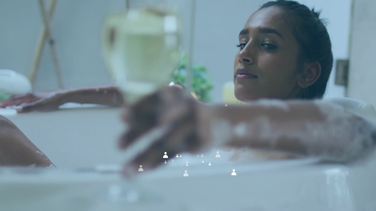 Settling into bathtub, woman raising wine glass and sipping for calm while health icons overlaying