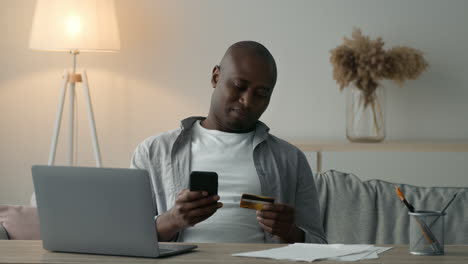 man using smartphone and credit card for online payment at home