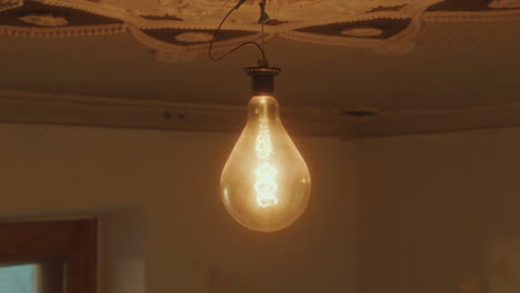 close-up of bulb lighting up and glowing under ornate ceiling in living room