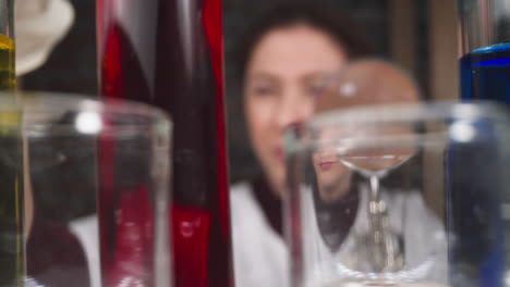 assistant with magnifying glass takes tube with red liquid