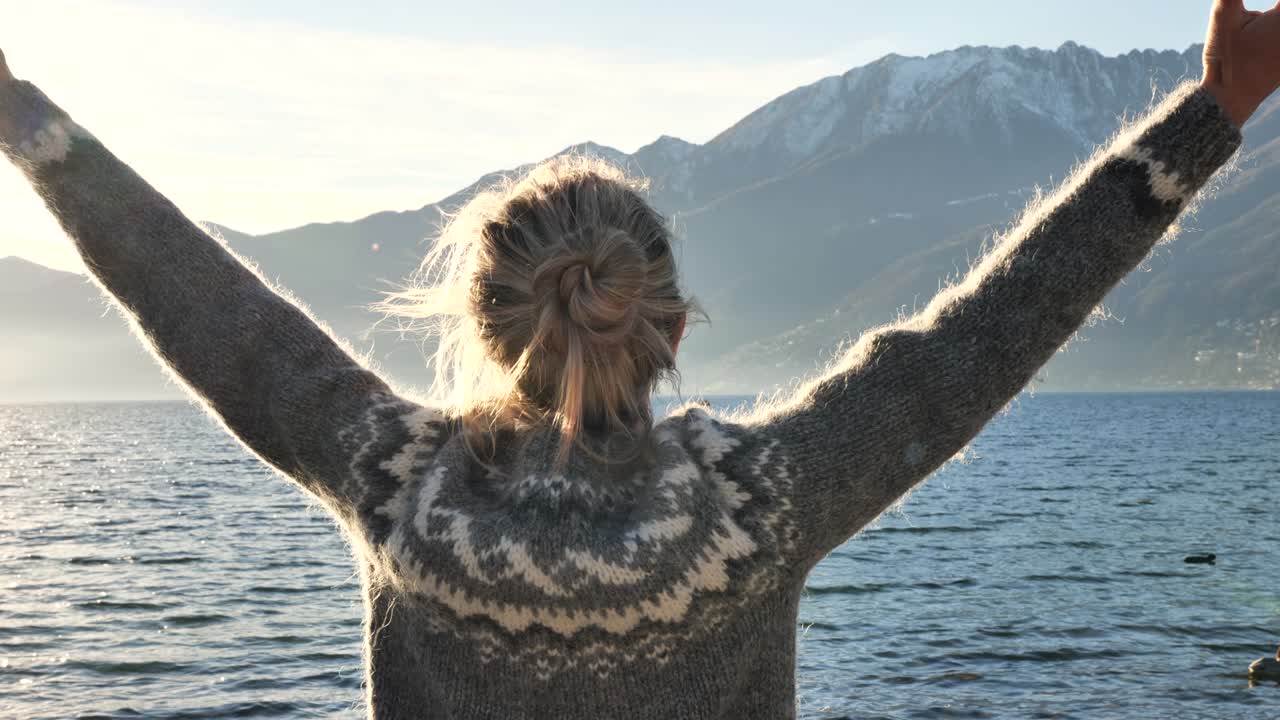 movimiento lento: mujer de pie junto al lago meditando y estirando los brazos. mujer se relaja junto al lago