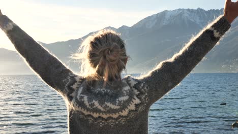 slow motion: female standing by the lake meditating and outstretching her arms. woman relaxes by the lake