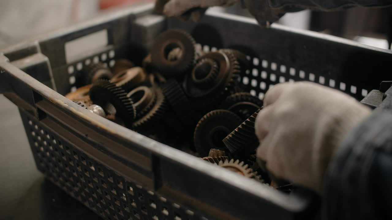 Worker Sorting Rusty Gears in a Bin