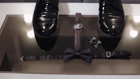 los accesorios del novio: una colección de gemelos, reloj, zapatos y una corbata de papagaio