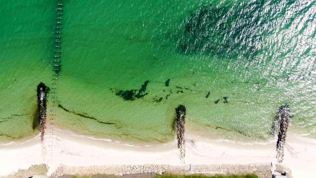태양은 모래 해안선 근처의 바닷물 잔물결에 반사되고, 공중 위에서 아래로 바라볼 수 있습니다.