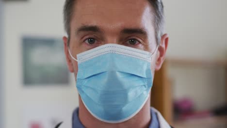 Portrait-of-caucasian-teacher-puttin-on-face-mask-while-in-classroom