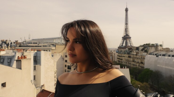 Beautiful young woman standing on a rooftop with the famous Tour Eiffel in the background, in Paris, France