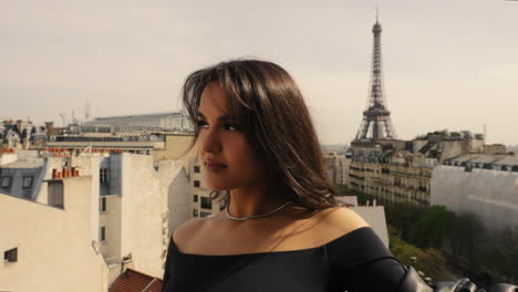 hermosa mujer de pie en un techo con el famoso tour eiffel en el fondo, en parís, francia