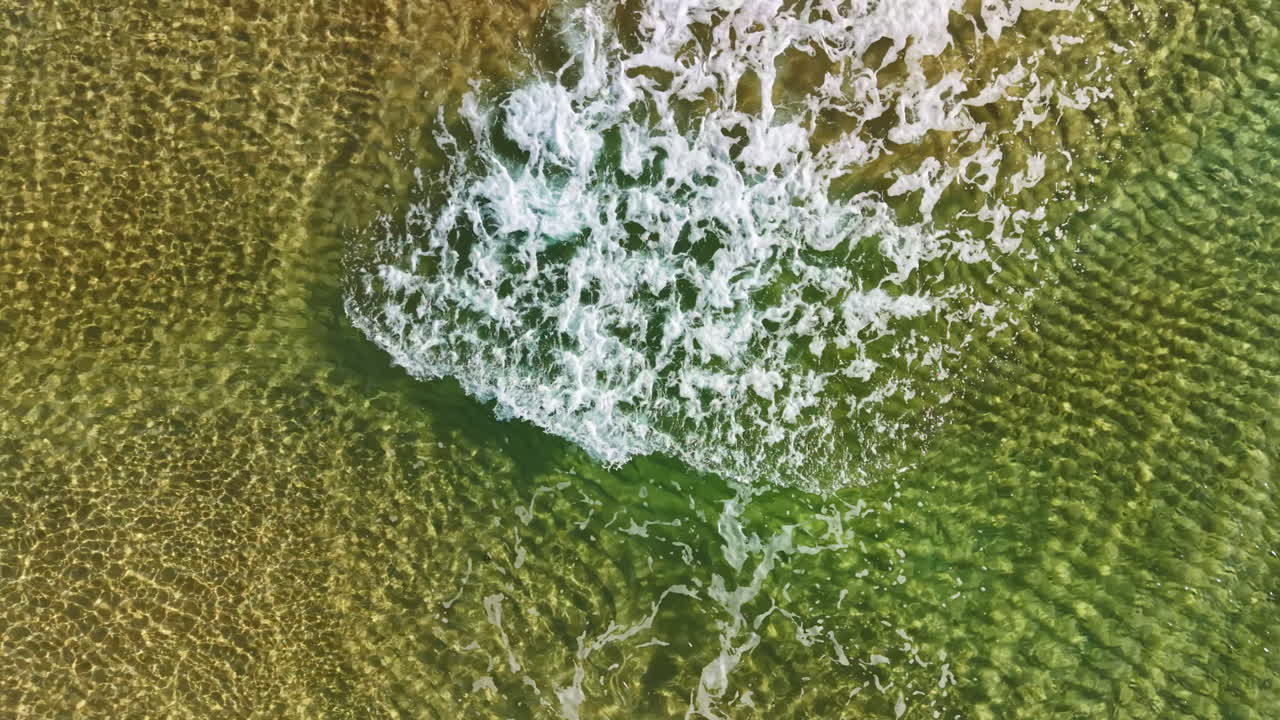 Onde increspate accarezzano la riva sabbiosa sotto il sole caldo in una spiaggia tranquilla durante il pomeriggio