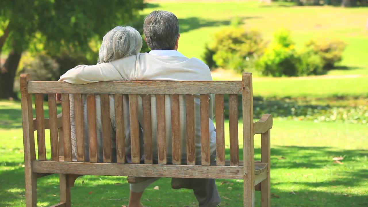 pareja madura sentada hablando al aire libre