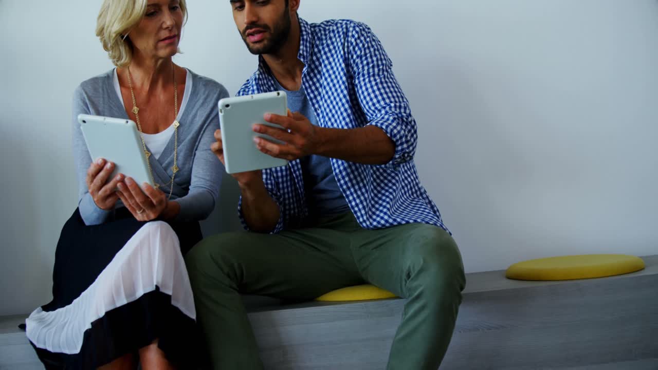 Male and female executives discussing over digital tablet