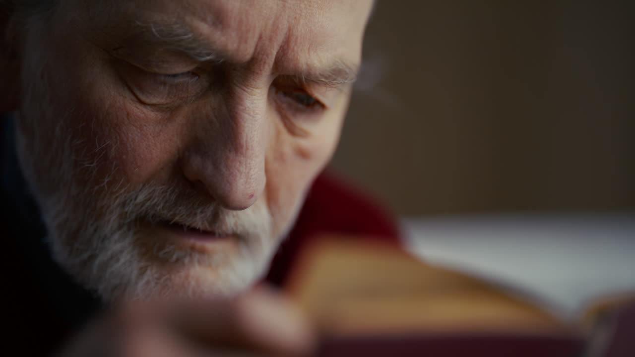 Close-up of an Elderly Man with a White Beard Reading a Book