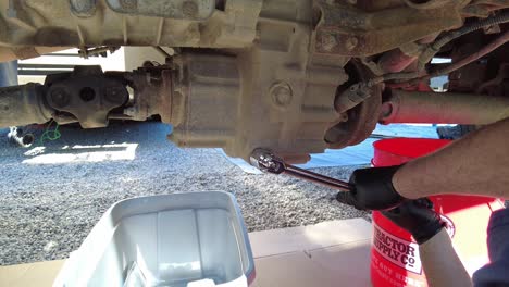 male hands holding a socket wrench with two hand loosening a bolt under a car, static close up