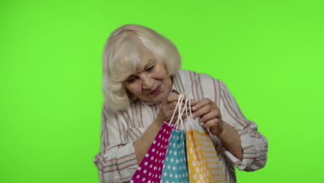 Abuela-Mayor-Levantando-Bolsas-De-Compras,-Celebrando,-Satisfecha-Con-La-Compra,-Descuento.-Clave-De-Croma