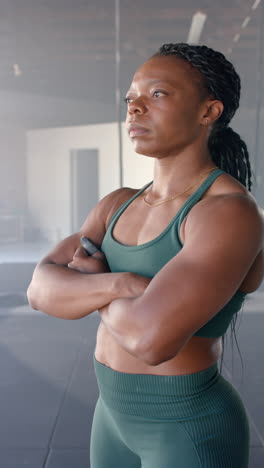 vertical video: confident woman in gym wearing sportswear, standing with arms crossed