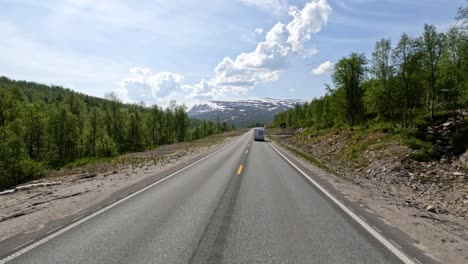 there is a motorhome travel rv with travelers on the way. driving a car on a road in norway at dawn. point-of-view driving. family vacation travel rv, holiday trip in motorhome, caravan car vacation.