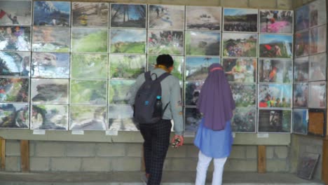 couple man and girl are watching photo gallery of volcanic eruption disaster from merapi volcano - merapi volcano, indonesia