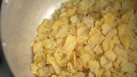 someone pouring cornflakes to a pot. preparing for making full menu of cereal. breakfast food. close up.