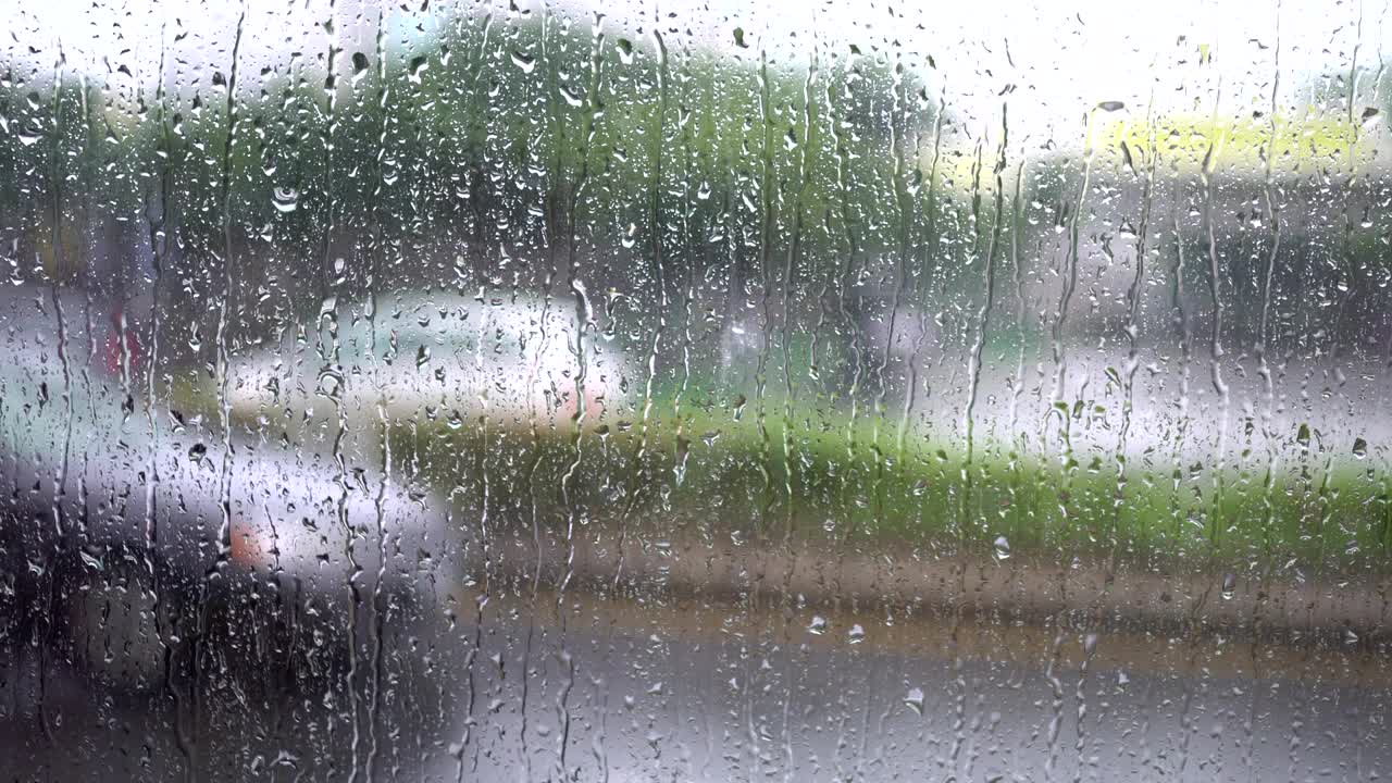 Street view on rainy day from the bus window. Raindrops of the glass window.The blurred background is the view of the street.