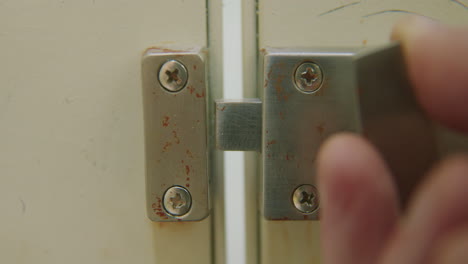 slow motion close-up of hand locking bathroom stall door and then moving away