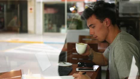 student drinking coffee and making notes in cafe